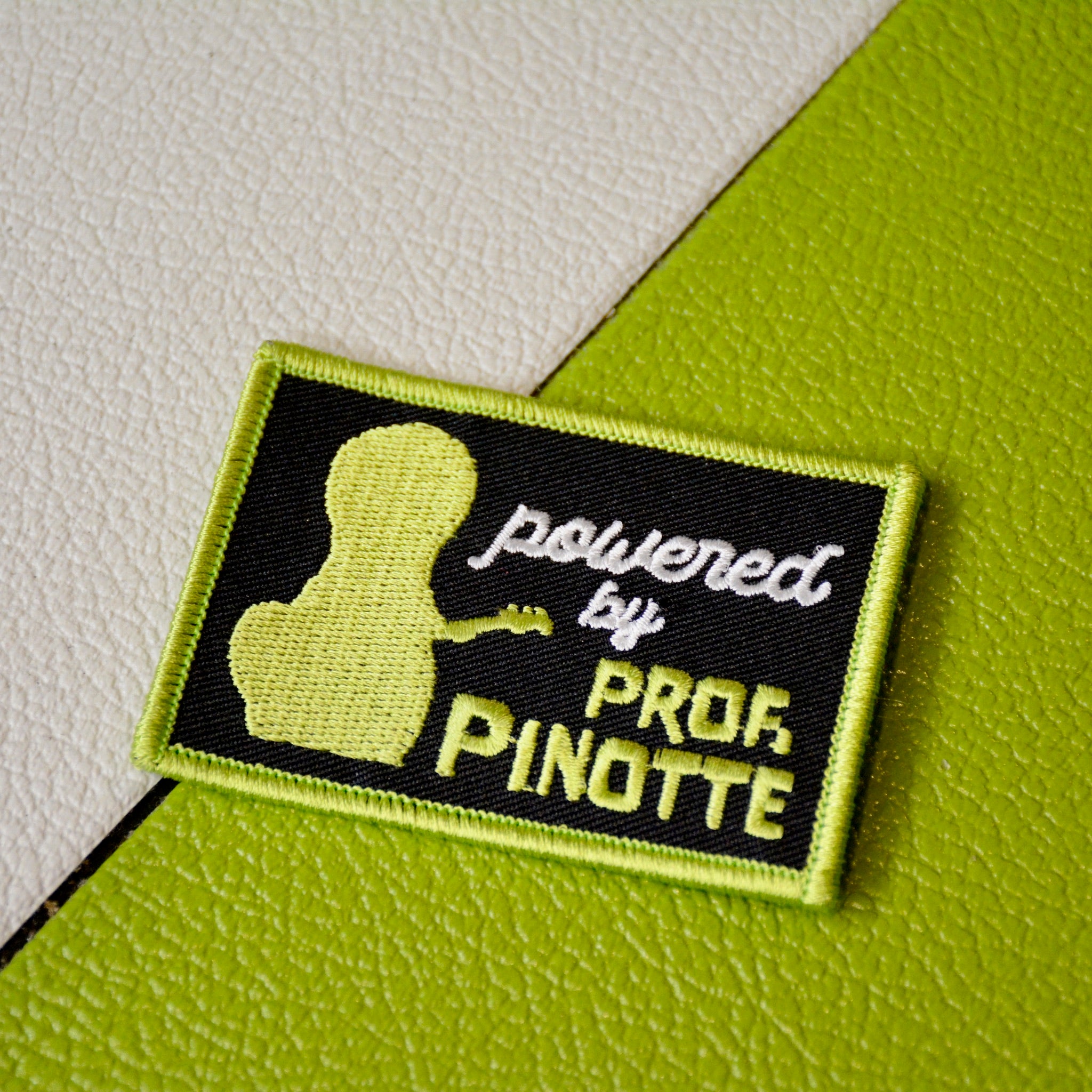 Embroidered “Powered by PROF. PINOTTE” iron-on guitar patch designed by GUPTech face on green background