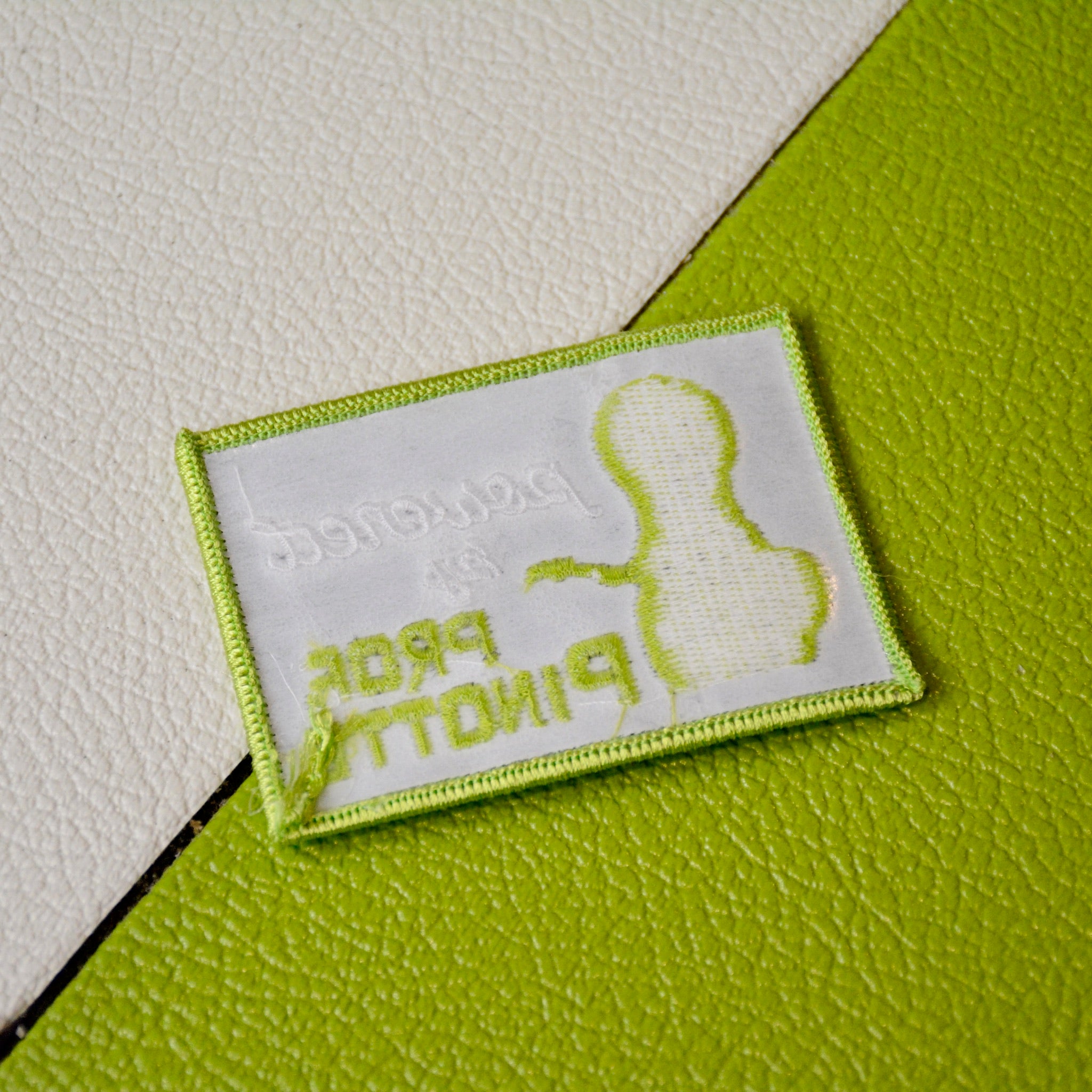 Embroidered “Powered by PROF. PINOTTE” iron-on guitar patch designed by GUPTech backing on green background