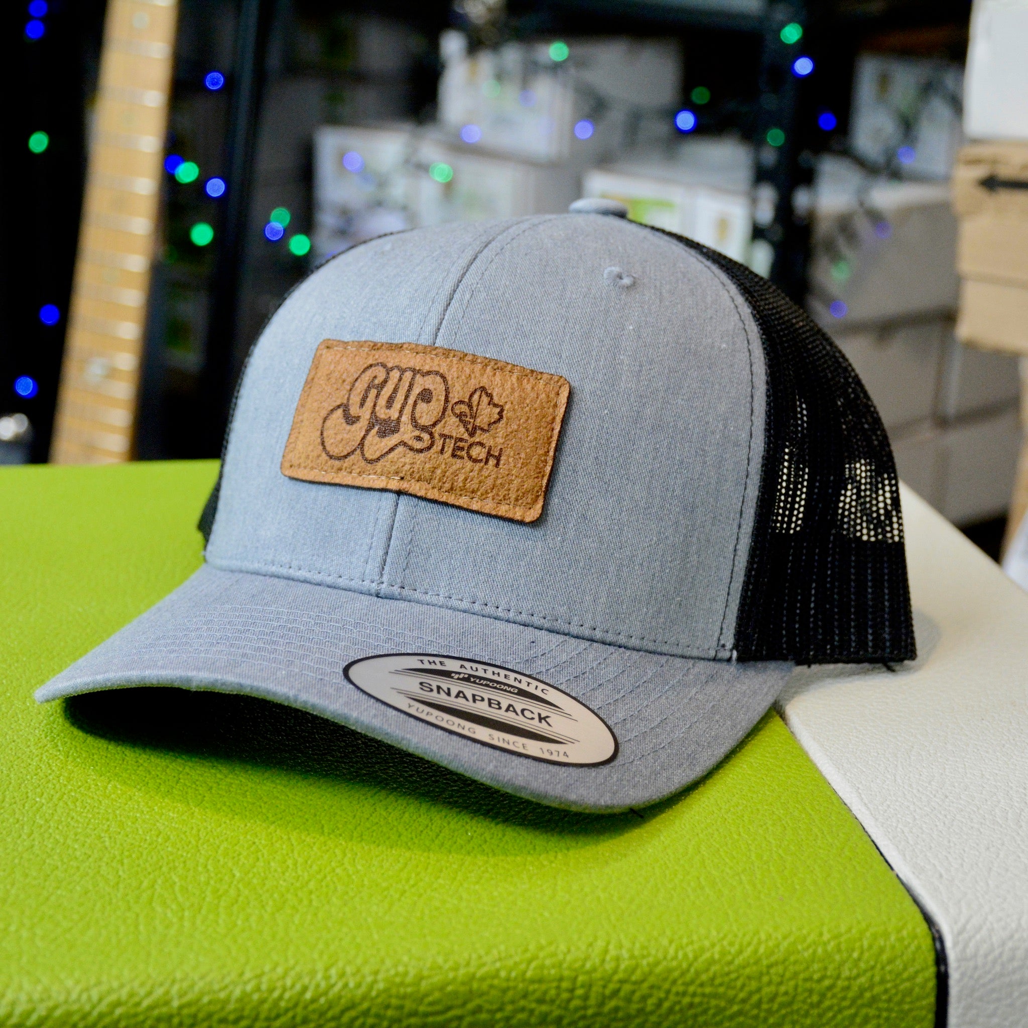 GUPTech burnt patch on a light grey and black mesh Yupoong snapback trucker cap.